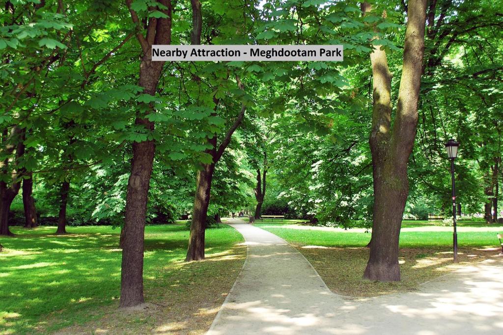 a path in a park with trees and a sign at Hotel O krishna in Noida