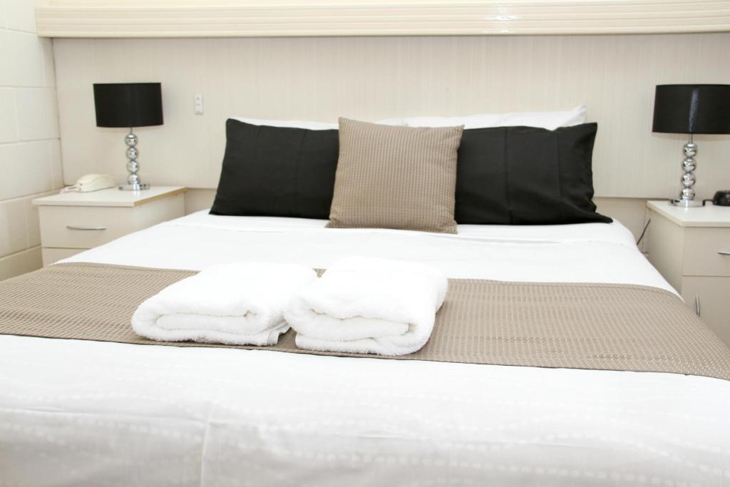 a bedroom with a white bed with towels on it at Renmark Motor Inn in Renmark
