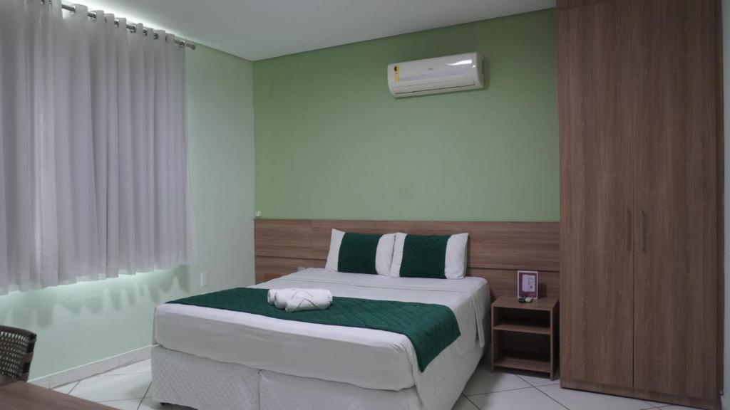 ein Schlafzimmer mit einem Bett mit einer grün-weißen Decke in der Unterkunft Domus Hotel Cidade Nobre - Ipatinga in Ipatinga