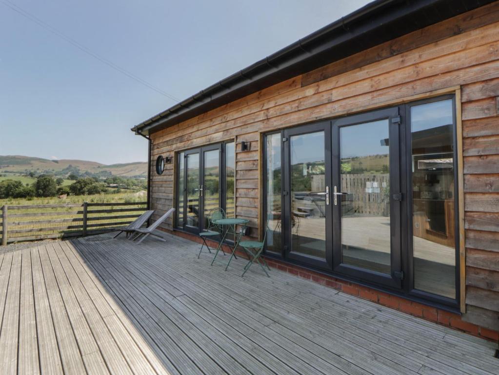 a cabin with a deck with a table and chairs at Tin Shed in Rhayader
