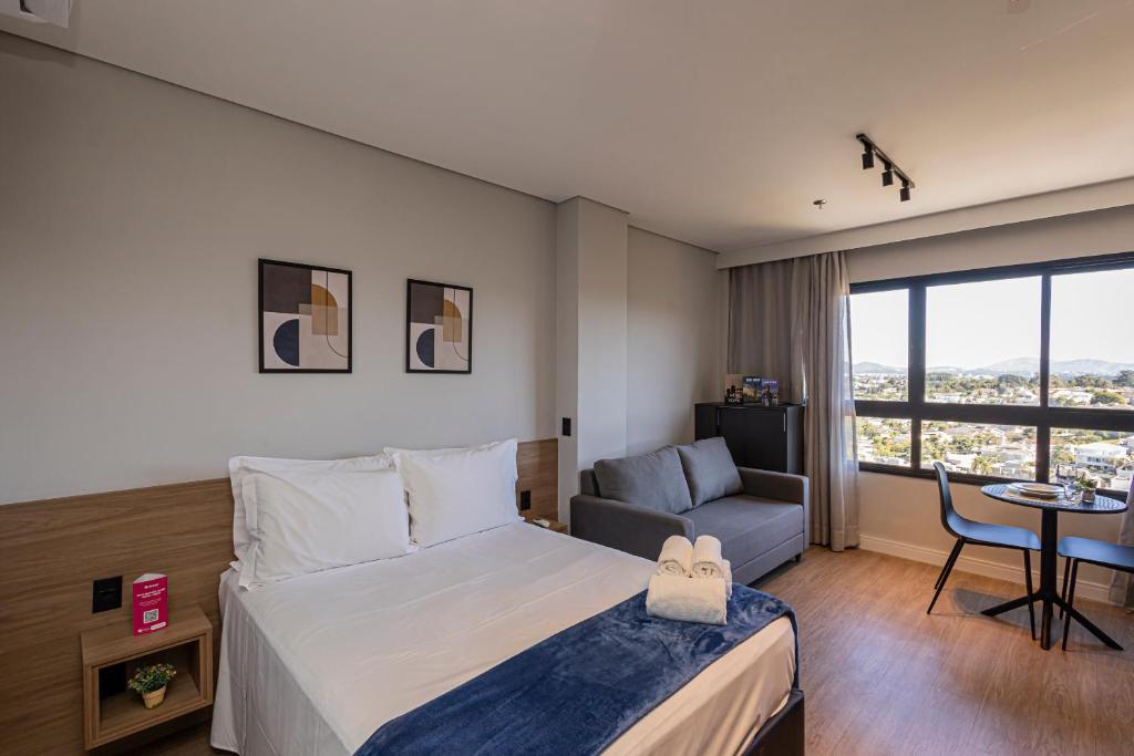 a hotel room with a bed and a chair and a table at Sky Design Residence in Barueri