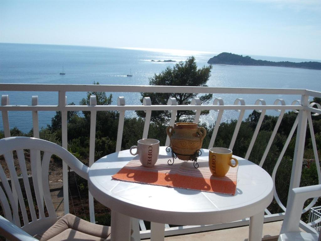 een tafel met twee kopjes en een pot op een balkon bij Apartments Liza Cavtat in Cavtat