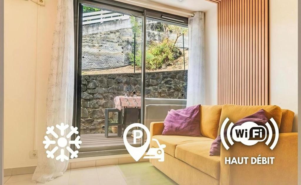 a living room with a couch and a large window at Le Saphir in Saint-Denis
