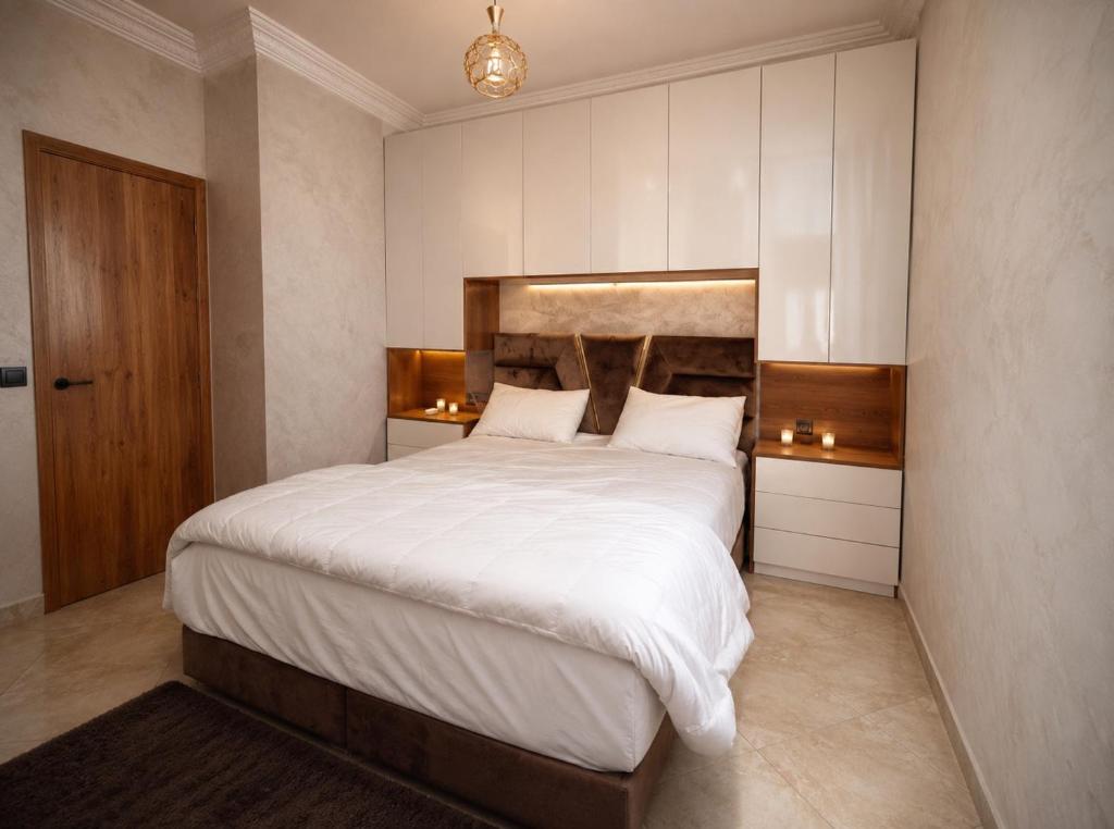 a bedroom with a large bed with white sheets at Modern and Cozy in Agadir