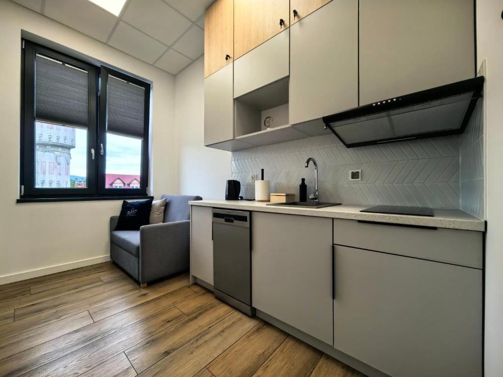 a kitchen with white cabinets and a couch in a room at POPIELATE Apartamenty in Żywiec