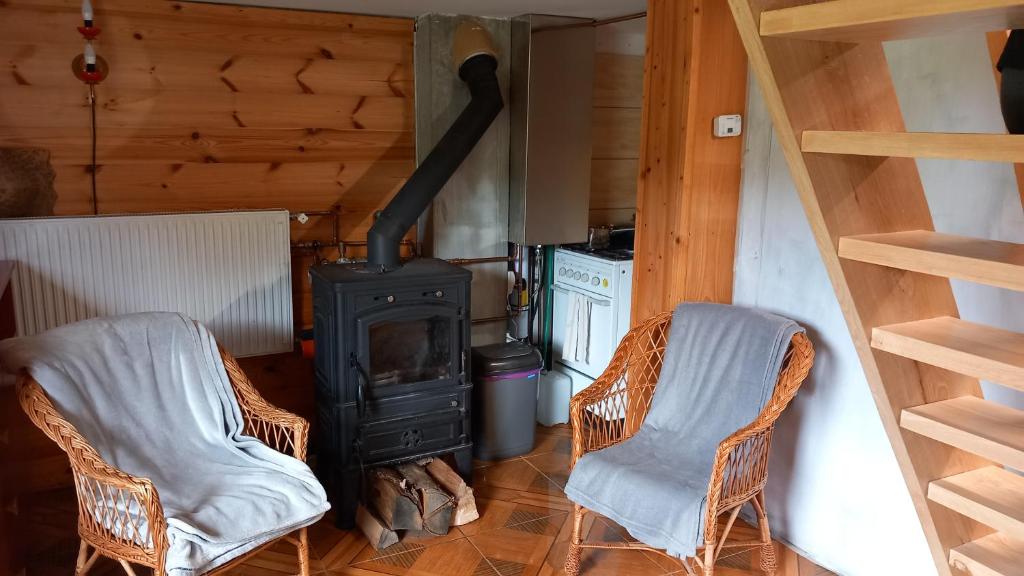 a living room with two chairs and a stove at Chata Milka in Medzilaborce