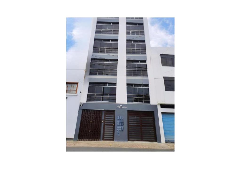 a tall white building with a brown door at Apartamentos "APPART D'ELIETTE" in Trujillo