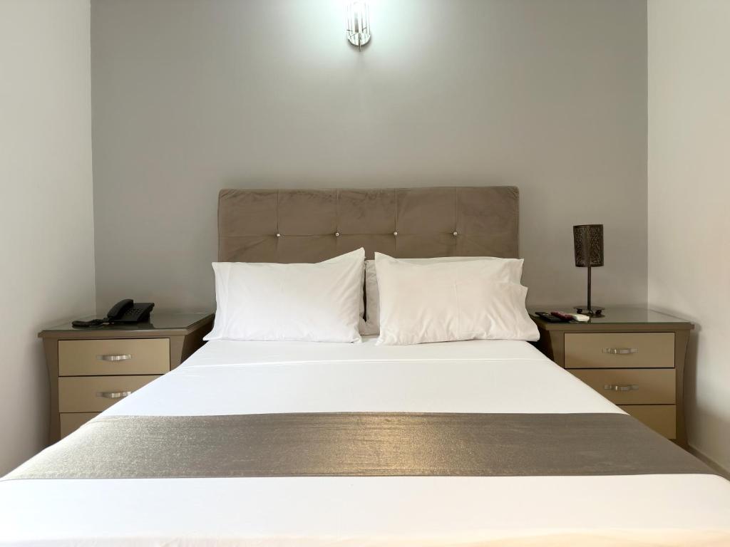 a bedroom with a large bed with two night stands at Hotel Roosevelt Plaza in Cali