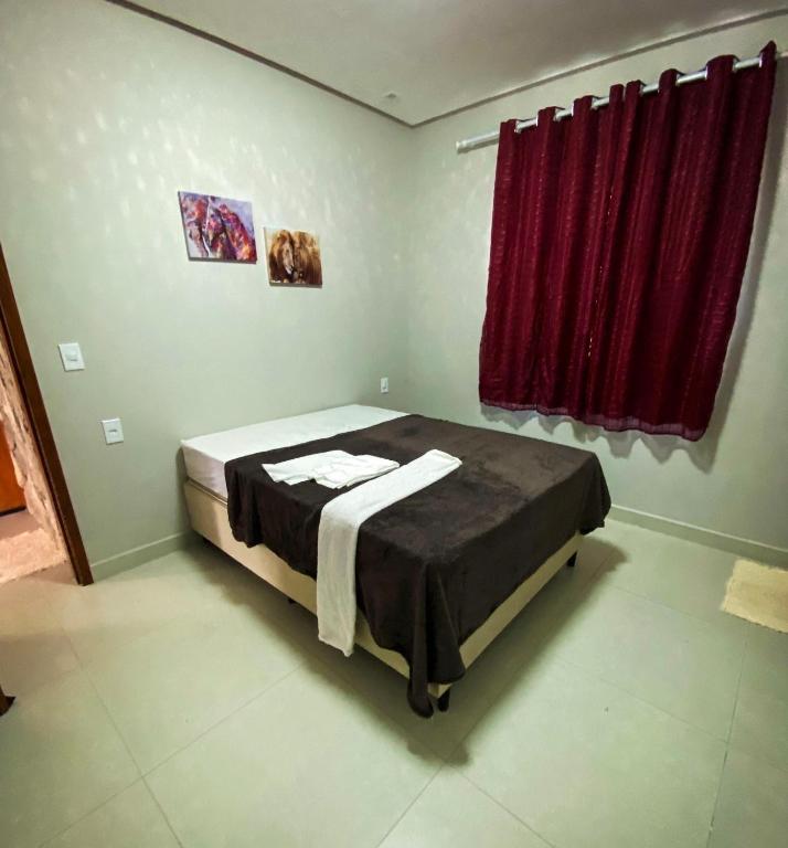 a bedroom with a bed with a red curtain at Espaço Sonhos da Serra in Bananeiras