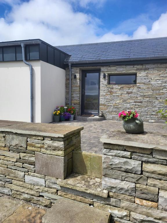 a stone house with a stone wall and a garage at Rose Meadow Lodge in Liscannor