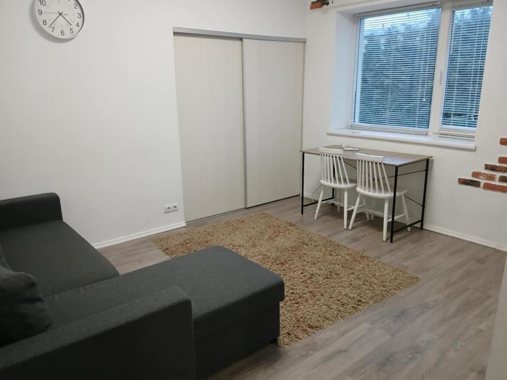 a living room with a couch and a table and a clock at Pärnade Apartment in Paikuse