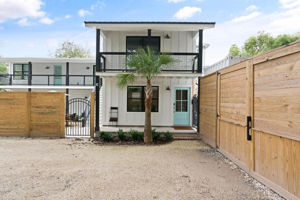 a house with a palm tree in front of a fence at Coastal Escape for 2 - Pool, Fire Pit & Beach Access in Saint Simons Island
