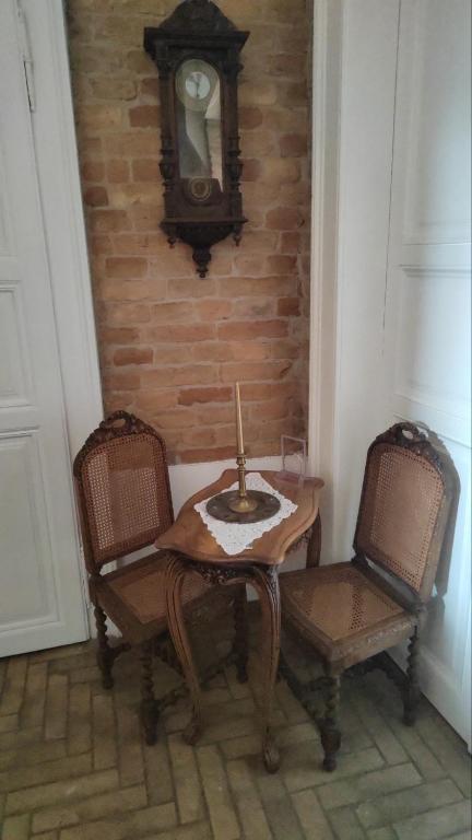 a table with two chairs and a clock on a brick wall at Vila Olga in Sombor