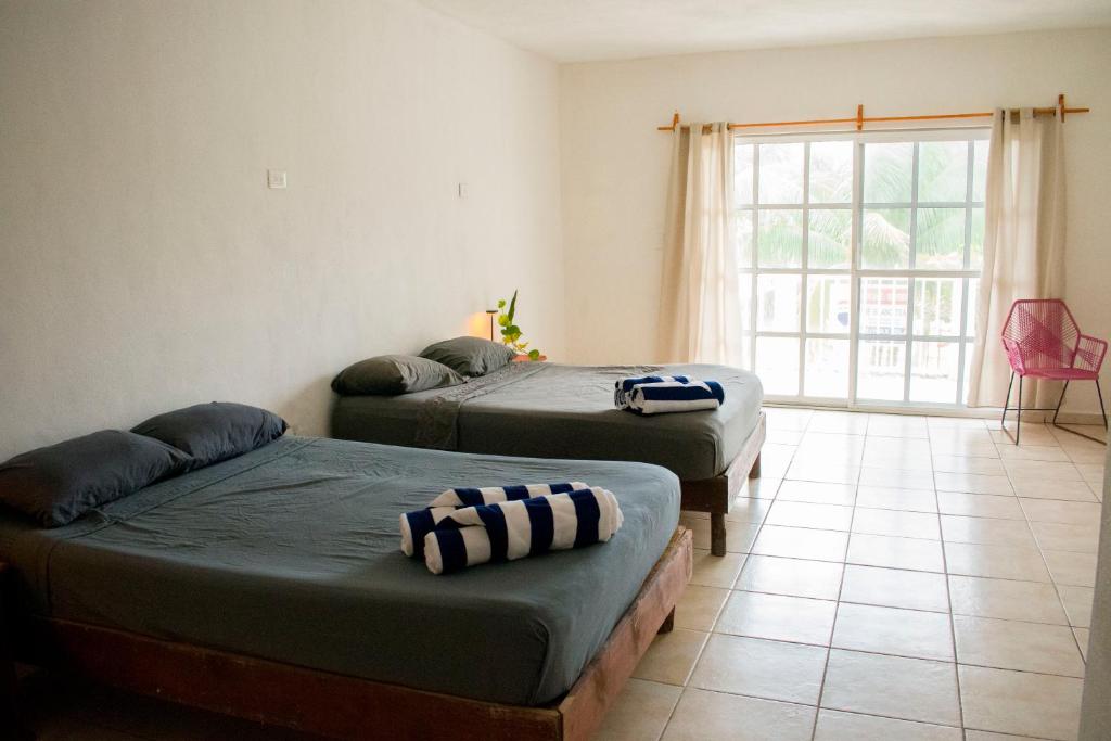two beds in a room with a window at Balu Hotel in Isla Mujeres
