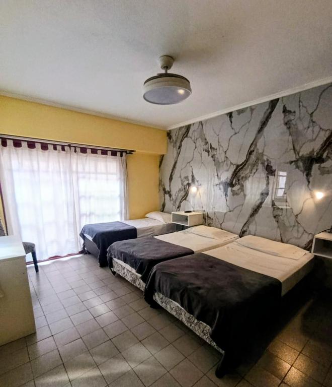 a bedroom with two beds and a stone wall at Kairos in Buenos Aires