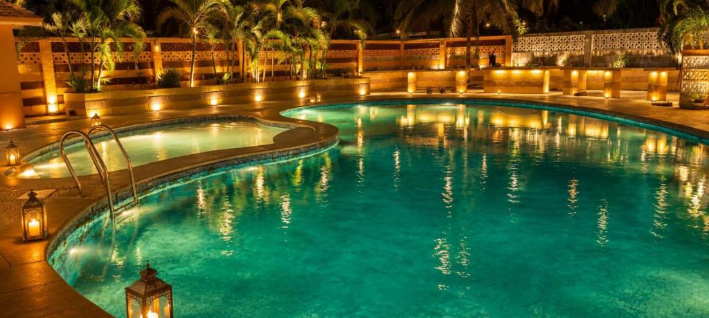 a swimming pool at night with lights in it at P'almshore Ecr' Resort in Mahabalipuram