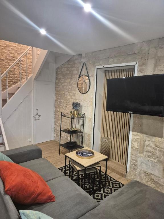 a living room with a couch and a flat screen tv at chic apartment and zen in Chauray