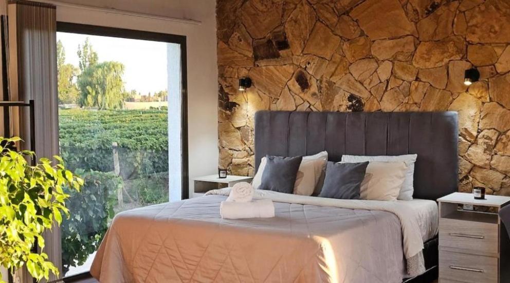 a bedroom with a large bed with a stone wall at Rincon del Malbec 3 in Ciudad Lujan de Cuyo