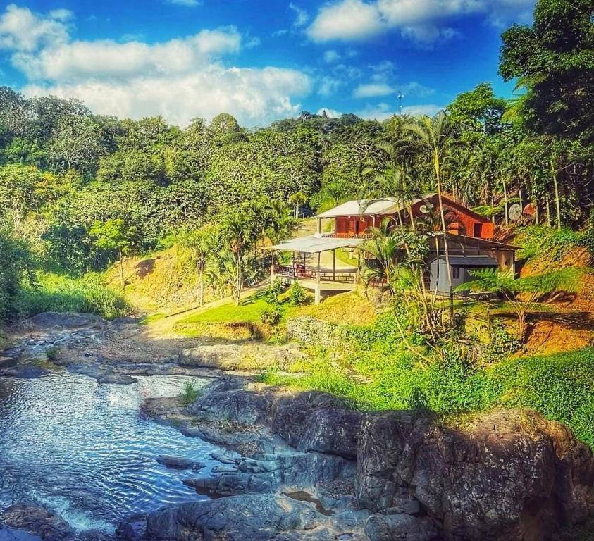 a house on top of a hill next to a river at Naranjito River Retreat Events & Groups Sleeps 13 in Naranjito