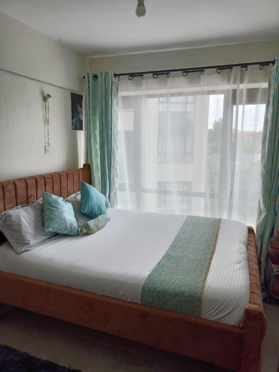 a bedroom with a large bed with a window at Le Kirstel Suites in Kiambu