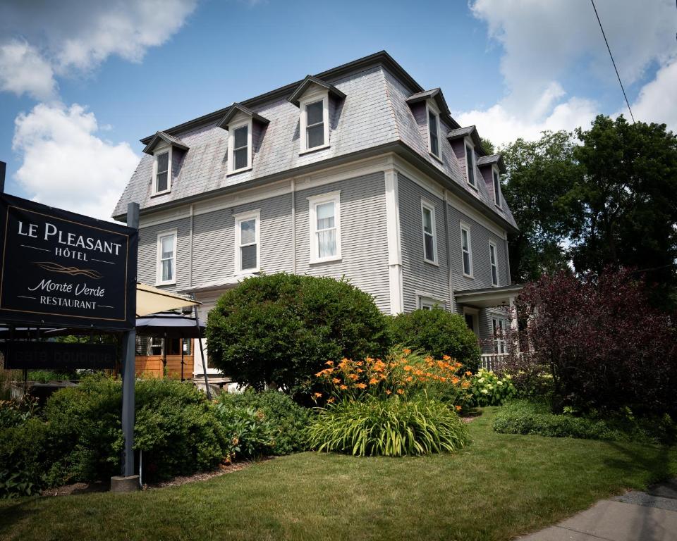 a large house with a sign in front of it at Le Pleasant Hôtel in Sutton