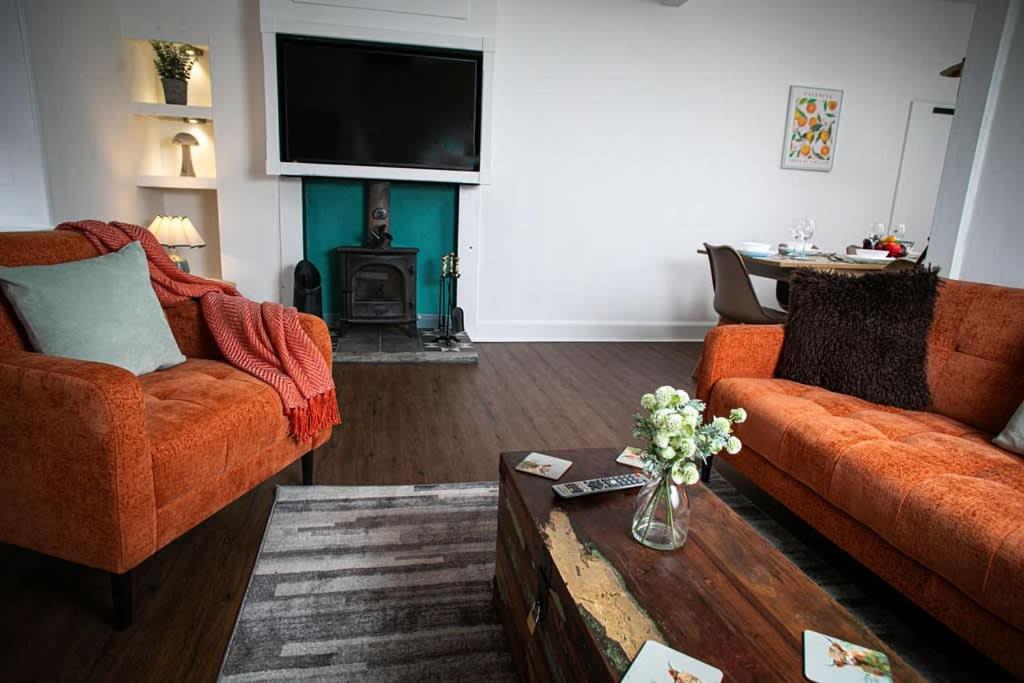 a living room with two orange couches and a coffee table at Castle Grant - 4 Bed Cottage in Gardenstown in Gardenstown