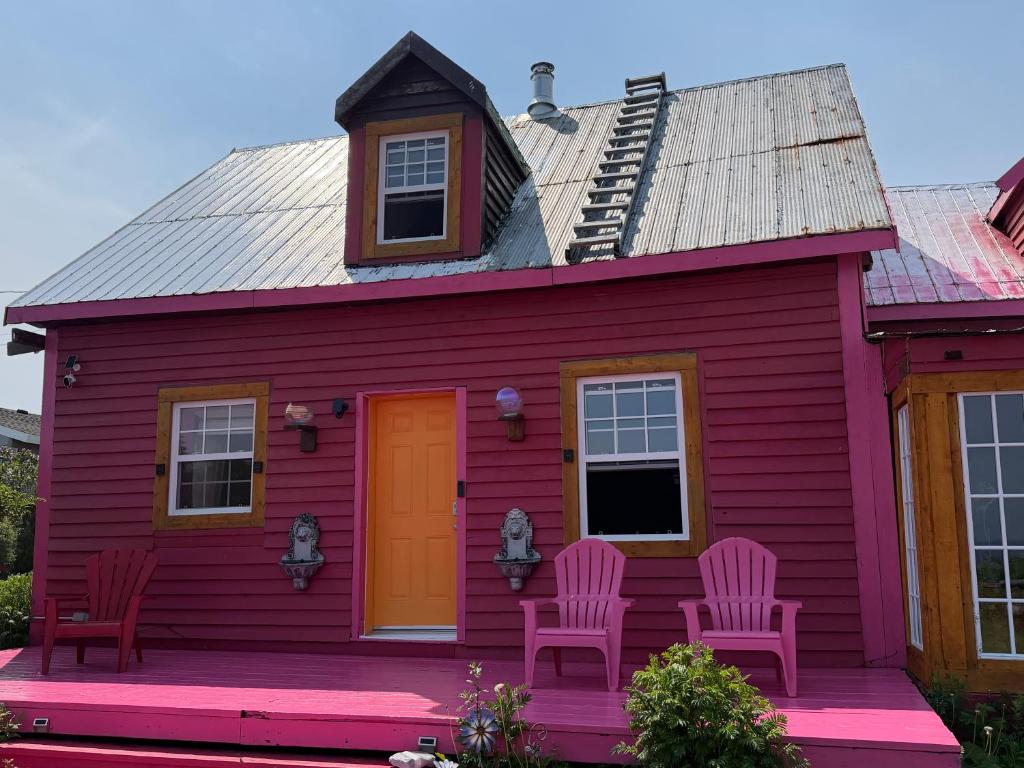 ein rotes Haus mit zwei Stühlen und einer orangefarbenen Tür in der Unterkunft La Forillonne in Gaspé