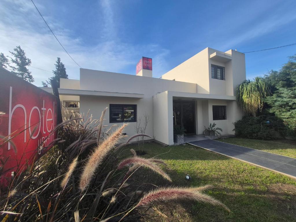 a white house with a red wall and grass at Hotel Urbana in Córdoba