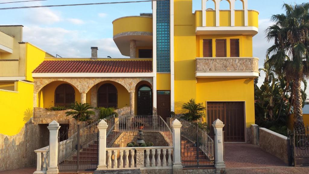 una casa gialla con una scala di fronte di B&B La Collina a Collepasso