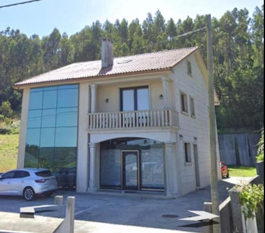 a house with a car parked in a parking lot at Casa Vilanova Costa da Morte in Cee