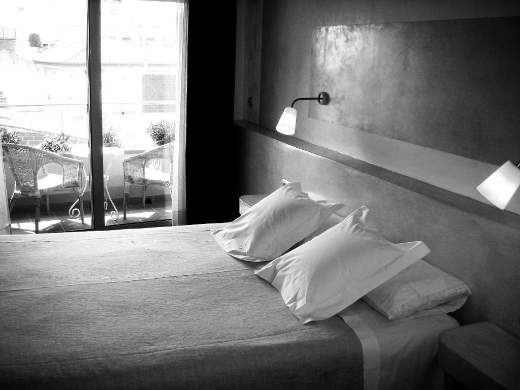 1 dormitorio con cama con almohadas y ventana en Hotel Carmen en Rosas