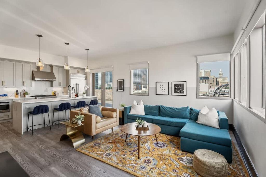 a living room with a blue couch and a kitchen at Corner Penthouse w Private Balcony Hotel Suite in New Orleans