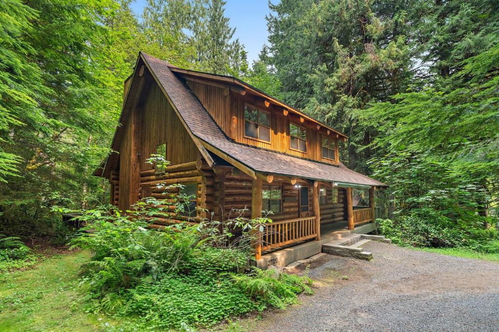 a large wooden cabin in the middle of a forest at Creekside Log Cabin - Fireplace - Mt Hood in Mount Hood Village
