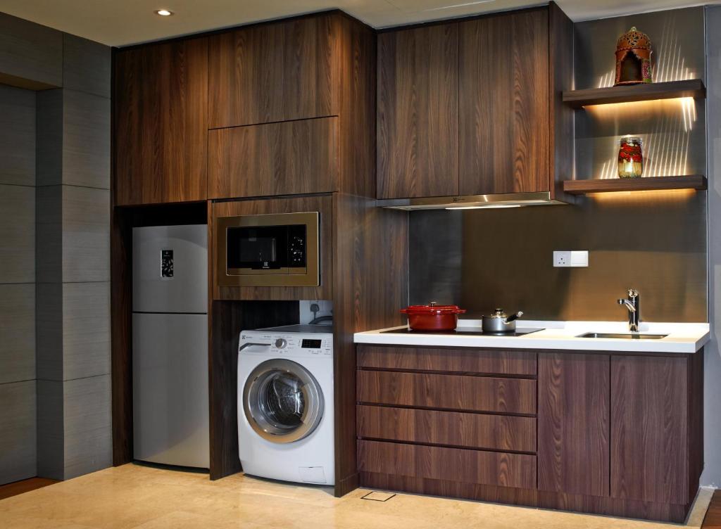 A compact apartment kitchen with a refrigerator, microwave and washing machine.