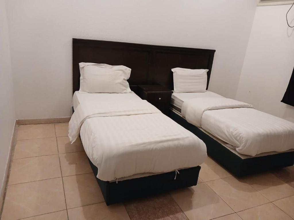 two beds with white sheets in a room at قصر أبها للشقق المفروشة in Abha