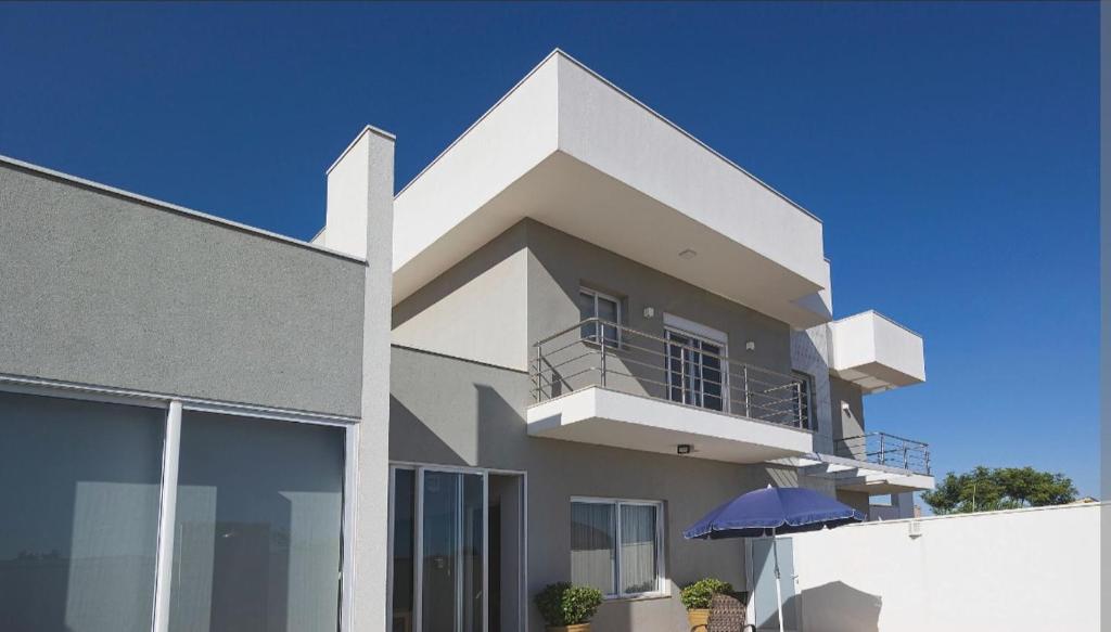 a white building with a balcony and an umbrella at Casa lunar in Belfort Roxo