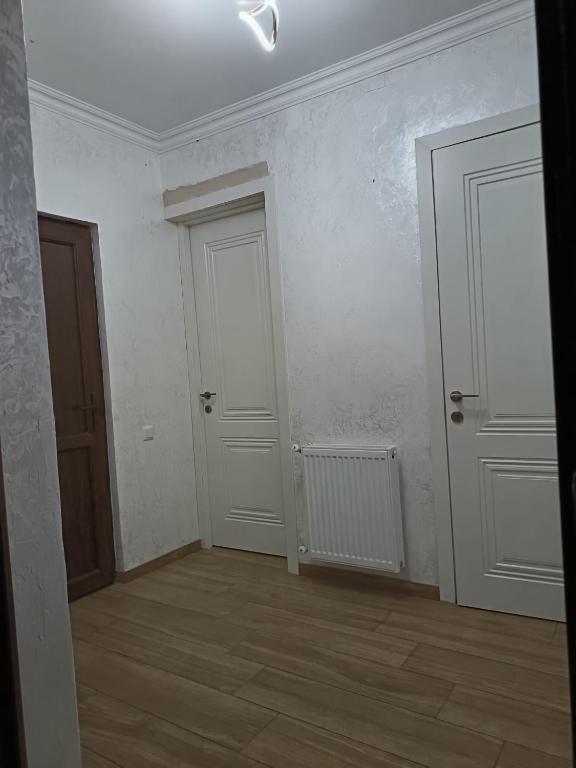 an empty room with two white doors and a wooden floor at Sunny Garden House in Ch'aisubani