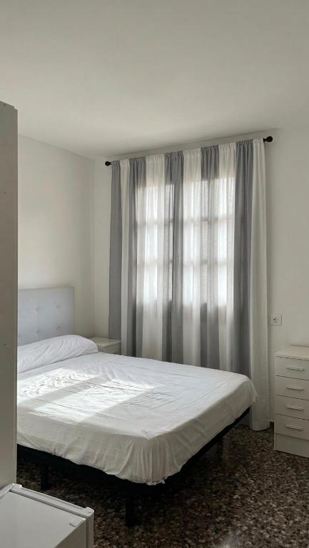 ein Schlafzimmer mit einem weißen Bett und einem Fenster in der Unterkunft Hostal Parada in Viladecáns