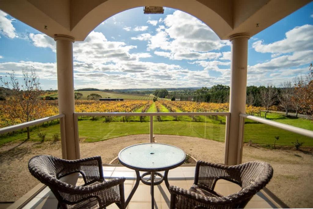 a porch with a table and two chairs and a view at Thicker Than Water Vineyard - 4 Bedroom Pool in McLaren Vale