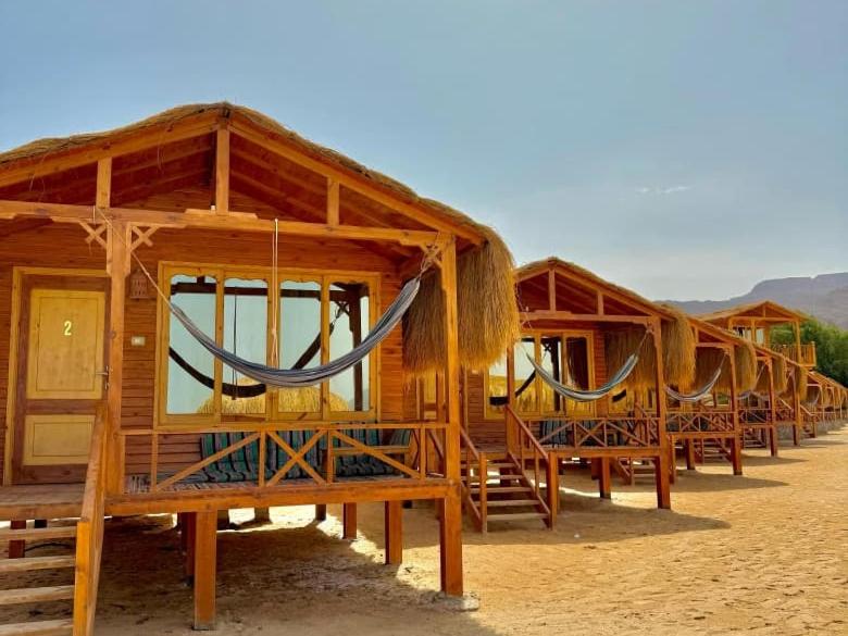 a row of wooden huts with hammocks in them at Love beach camp in Taba