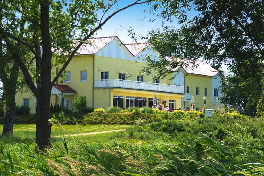 a large yellow building with a balcony in a park at Appartement im Seedomizil Kummerow in Kummerow