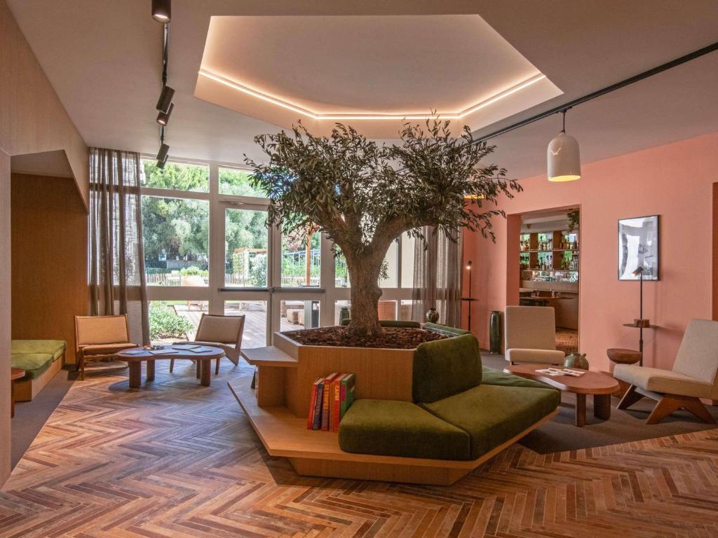 a living room with a tree in a planter at Novotel Nice Aéroport Cap 3000 in Saint-Laurent-du-Var