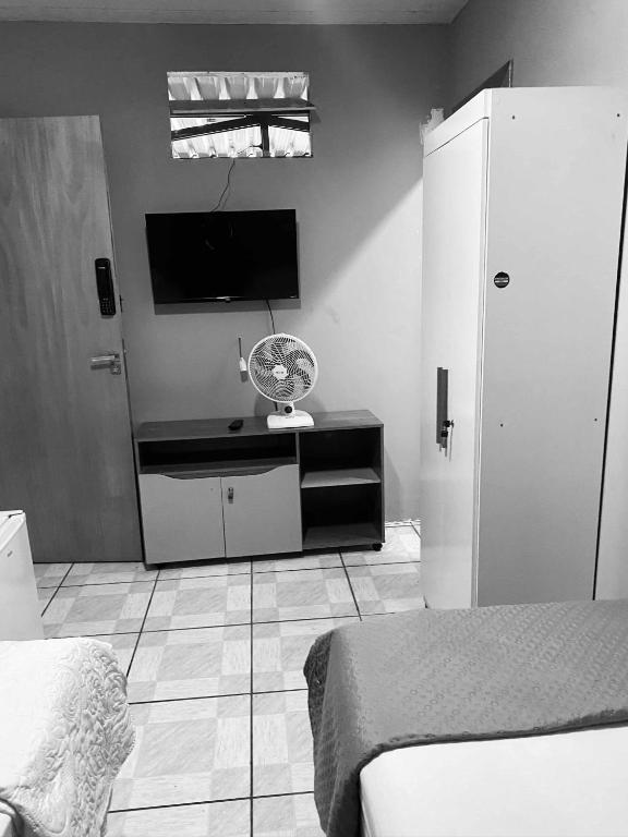 a bedroom with a room with a bed and a fan at quarto aconchegou 1 in Divinópolis