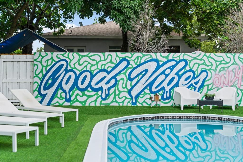 a swimming pool with chairs and a fence with graffiti at New Casa Eva Turfed Pool 5Br in Hallandale Beach