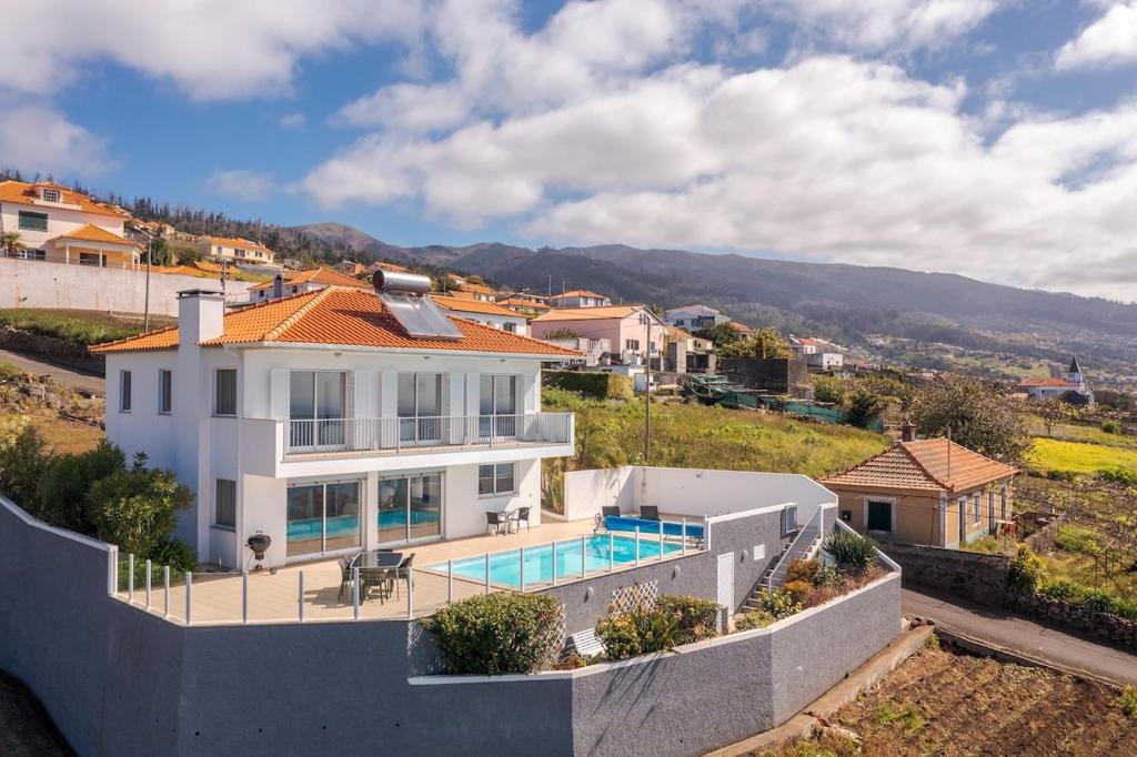 a large white house with a swimming pool at Villa Eldomar Heated Pool in Estreito da Calheta