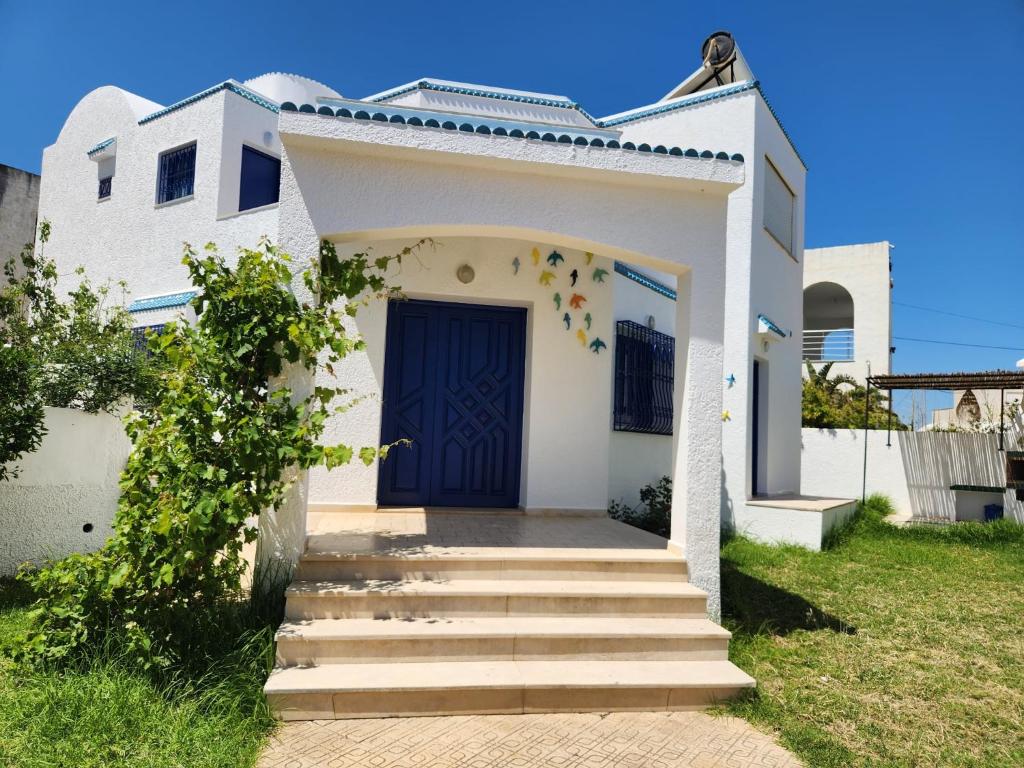 a white house with a blue door and stairs at Villa SiJoBa in Raʼs al Jabal