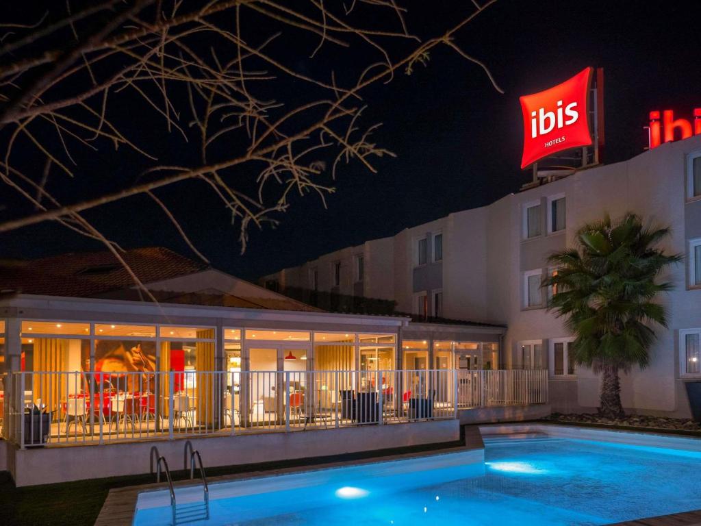 a hotel with a pool in front of a building at ibis Arles in Arles