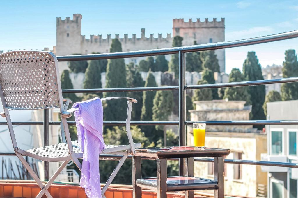 a chair sitting on a balcony with a glass of orange juice at Danezis City Stars Boutique Aparthotel in Rhodes Town