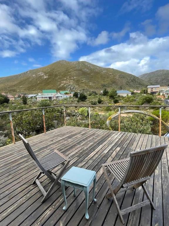 a wooden deck with two chairs and a blue table at Love Nest In Pringle Bay in Pringle Bay