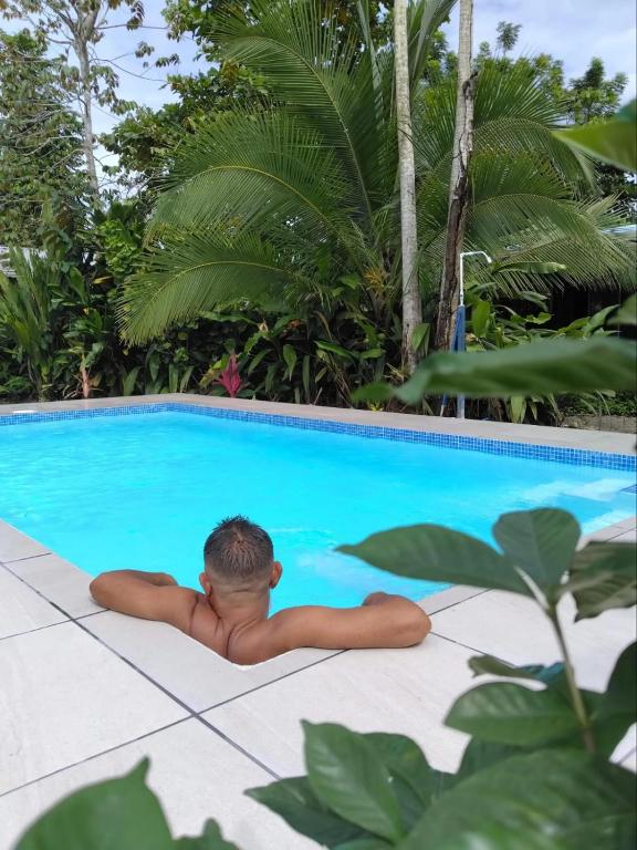 a young man laying in a swimming pool at Nueva Vida Birding Paradise in Puerto Jiménez